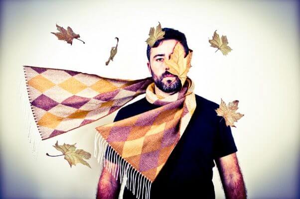 Una persona azotada por el viento del otoño, viendo pasar las hojas de los árboles, mientras permanece impasible.